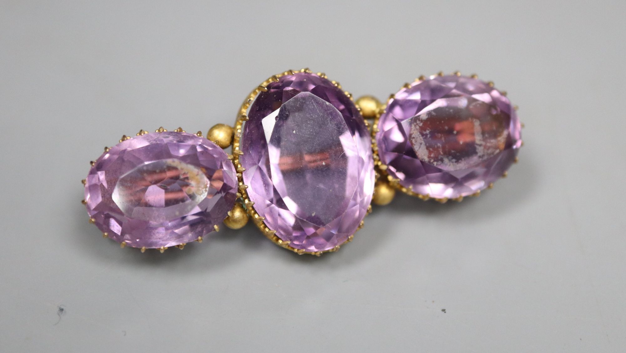 A Victorian yellow metal and three stone amethyst bar brooch, 4.25cm, later cased